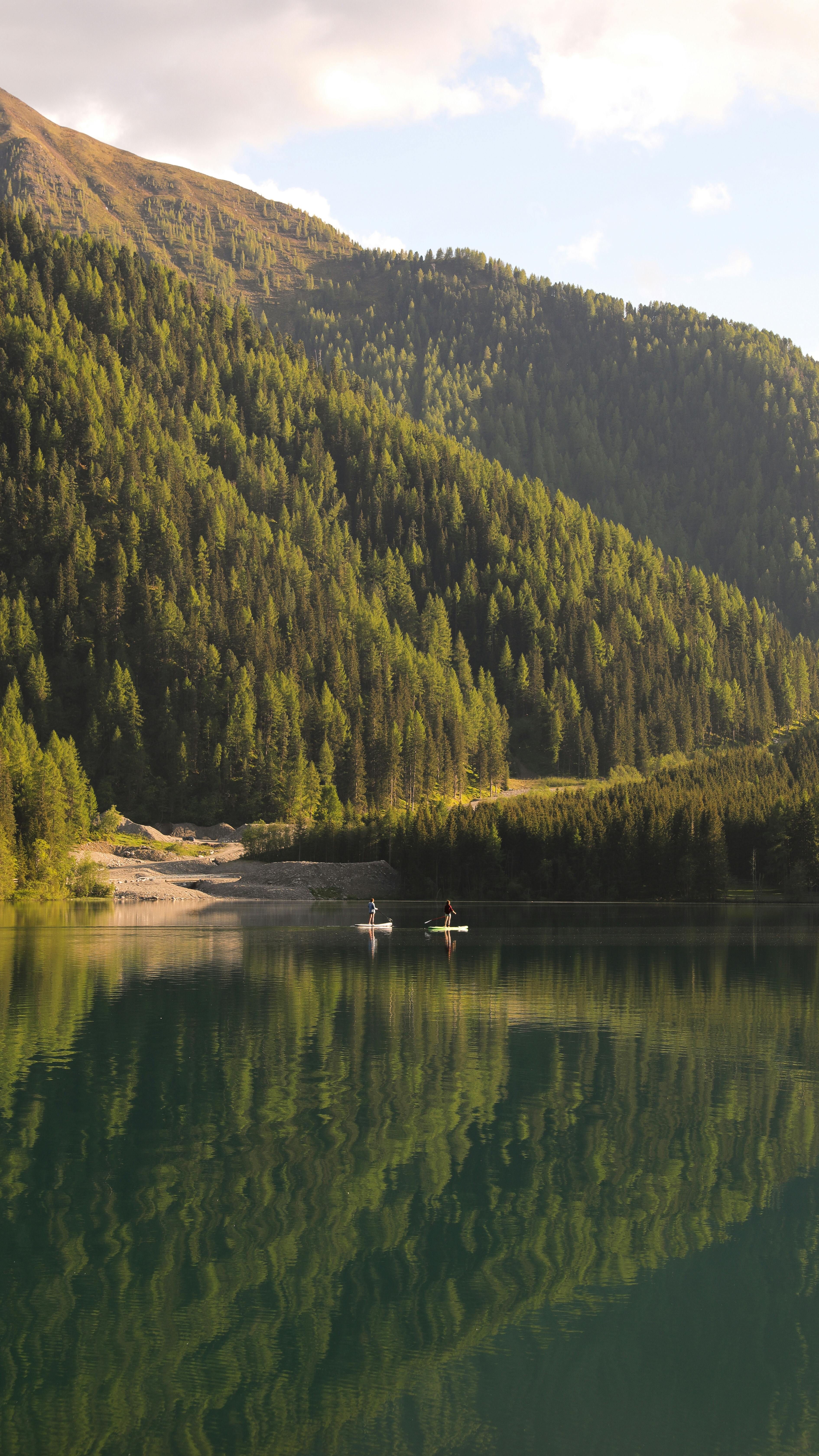 Stunning mountain landscape with a tranquil lake and forest reflections under a summer sky.