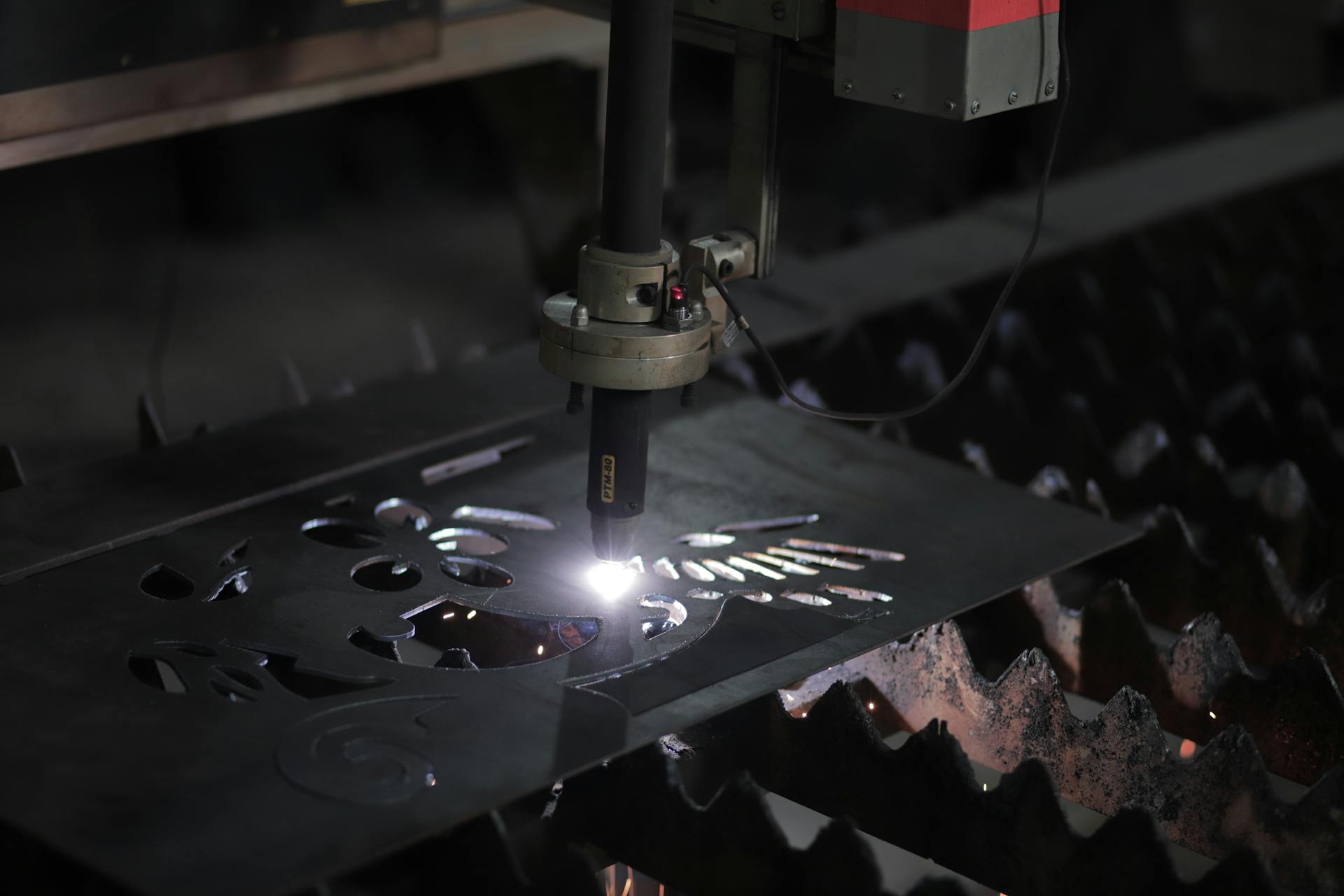 Close-up of a plasma cutting machine working on a metal sheet in an industrial setting.