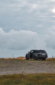 Black SUV navigating through a rural landscape, showcasing rugged terrain and overcast sky.