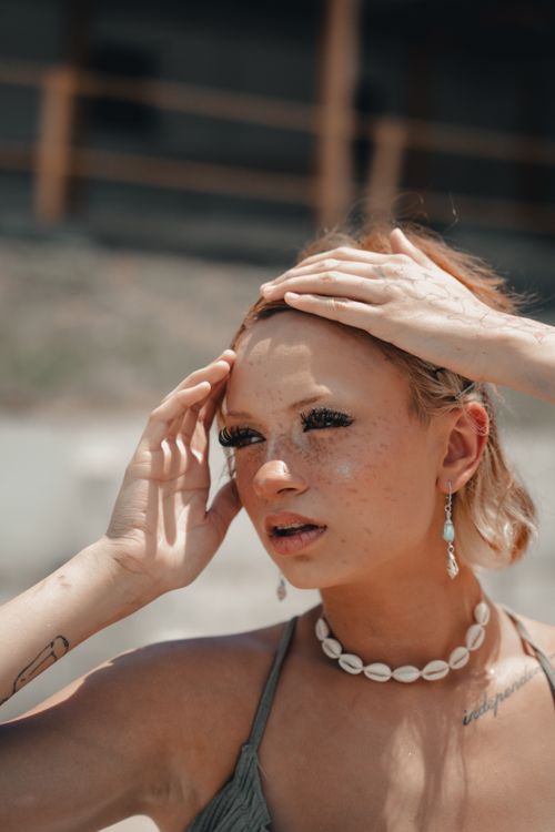 Free Portrait of a fashionable woman outdoors wearing a shell necklace and earrings. Stock Photo