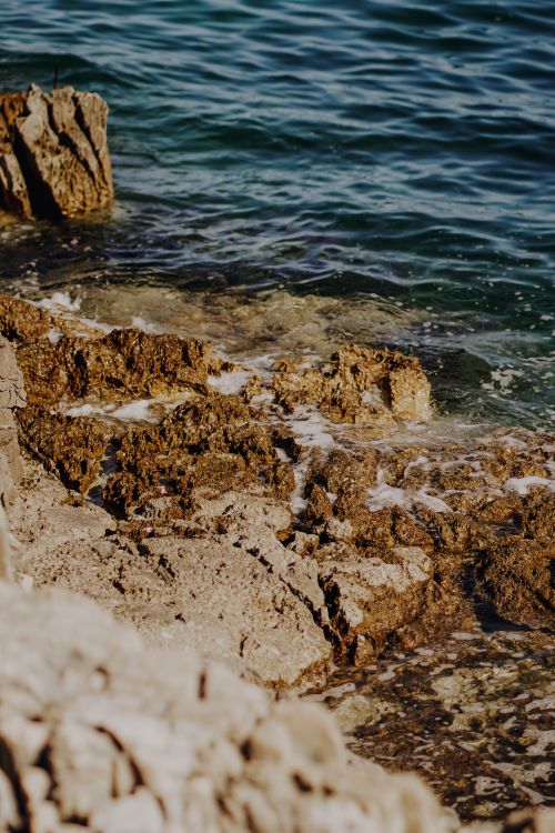Free Discover the beauty of rugged coastal rock formations by the tranquil blue sea. Stock Photo