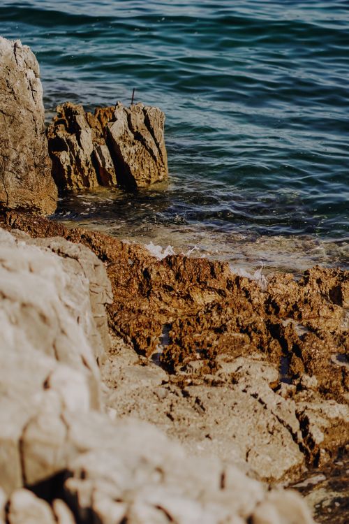 Free Scenic view of rugged rocky shoreline with crystal clear ocean waters. Stock Photo