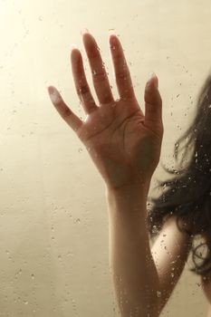 Close-up of a female hand with water droplets on glass, creating a dramatic and intimate scene.