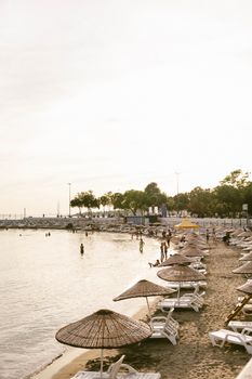 A serene beach with sunbeds and umbrellas at sunset, perfect for a relaxing vacation.