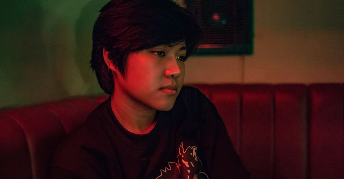 person sitting alone in a dark room, looking contemplative