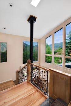 Bright interior space featuring large windows with mountain views and elegant wooden stairs.