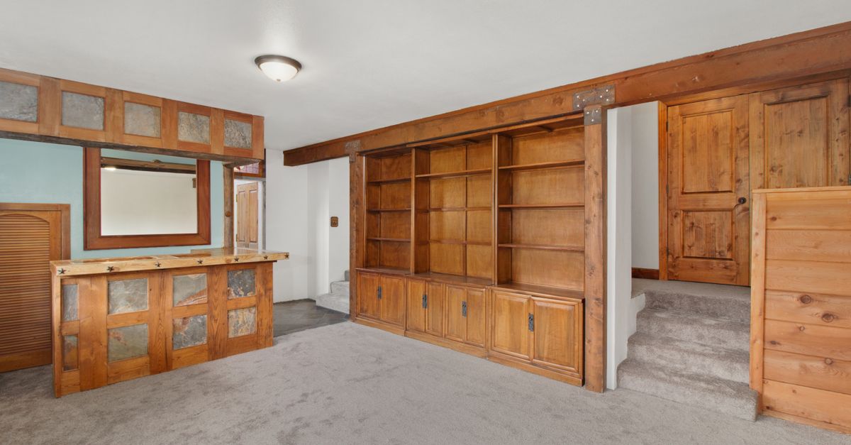 Empty room featuring wooden furniture, built-in shelves, and a home bar area.