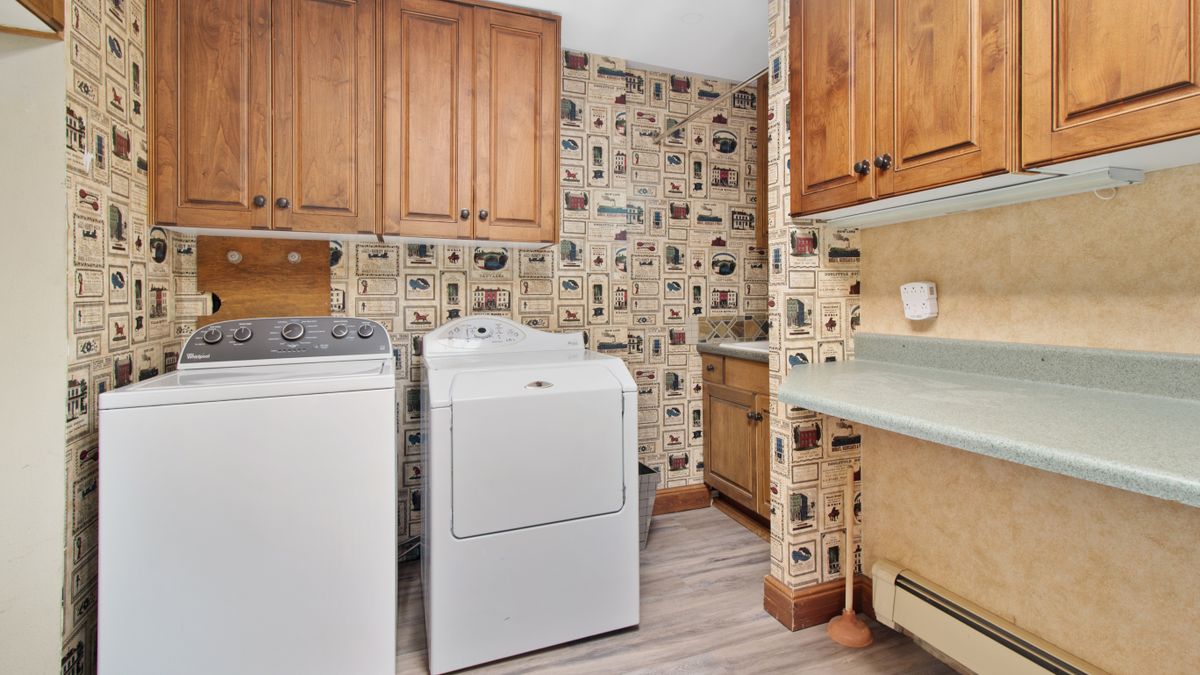 A laundry room with a washer and dryer under wooden cabinets.
