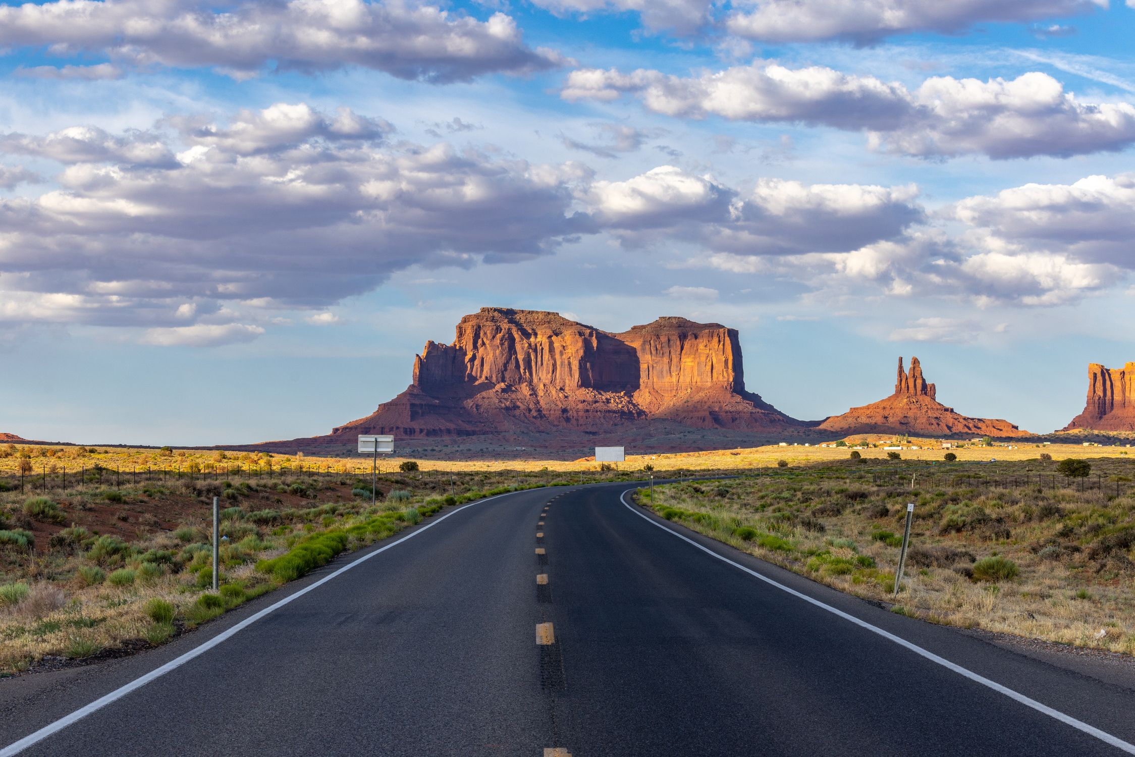 A picturesque road leading to Monument Valley with stunning sandstone formations under a vibrant sky.