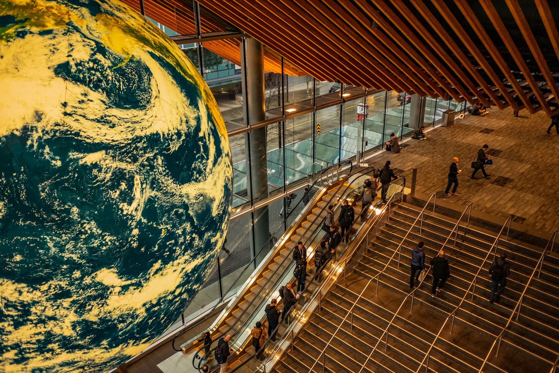 A high angle view of a bustling urban station, featuring escalators and a giant globe.