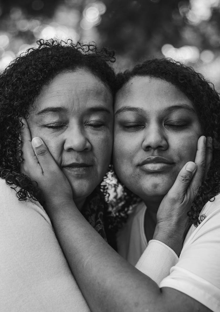 Black And White Photo Of A Mother And A Daughter Touching Their Faces With Hands