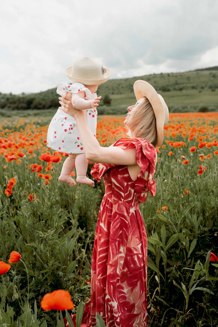 Woman Holding A Baby In A Red Poppy Field 