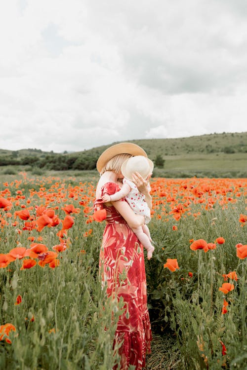 Woman Holding a Baby in a Poppy Field 