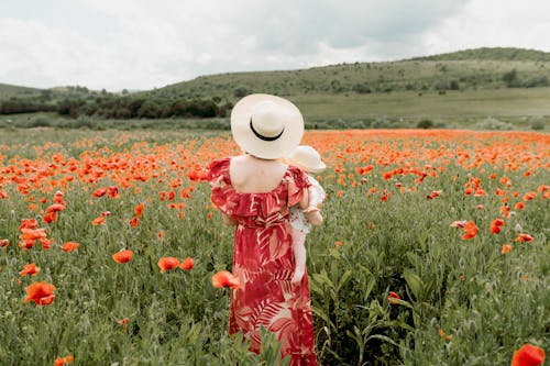 Woman with Baby on Hand Standing on Poppies Meadow