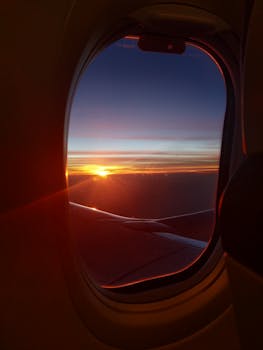 从飞机舷窗望去，云层之上日落绚烂，尽显航空旅行的壮美