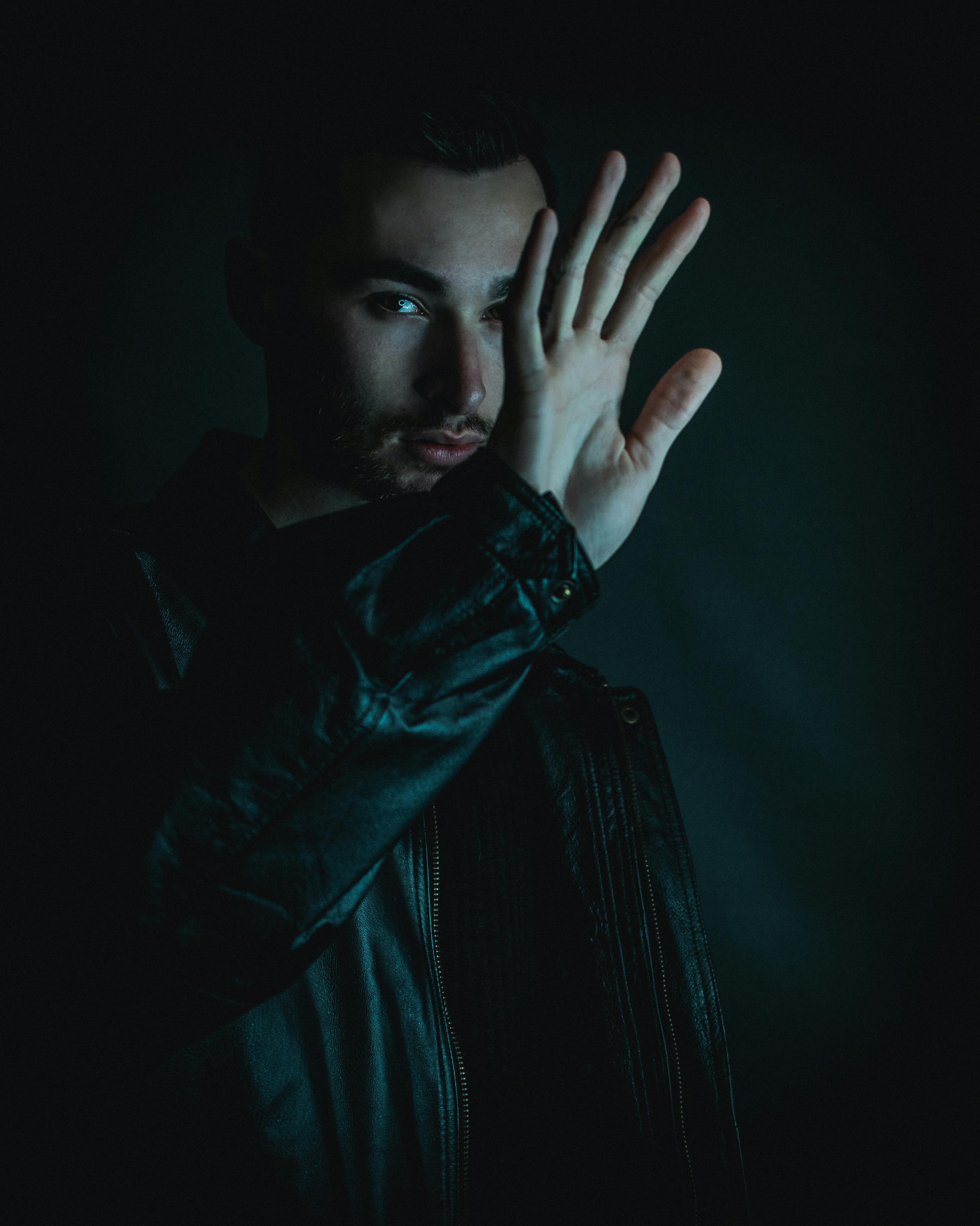 a man in black leather jacket holding his hand up