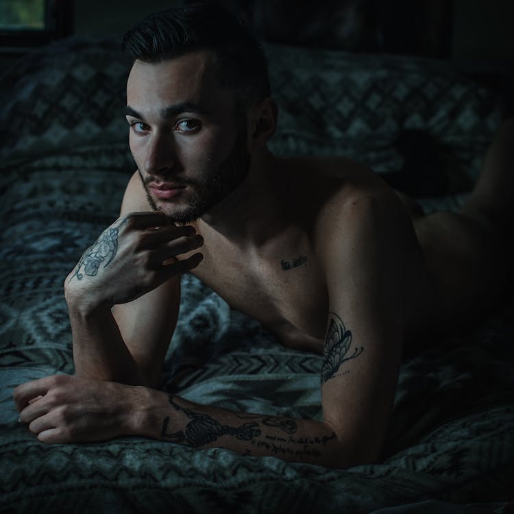 Naked Man With Tattoos Lying In Bed