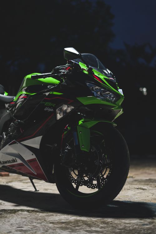 Free A vibrant Kawasaki Ninja ZX-6R motorcycle parked outdoors at night. Stock Photo