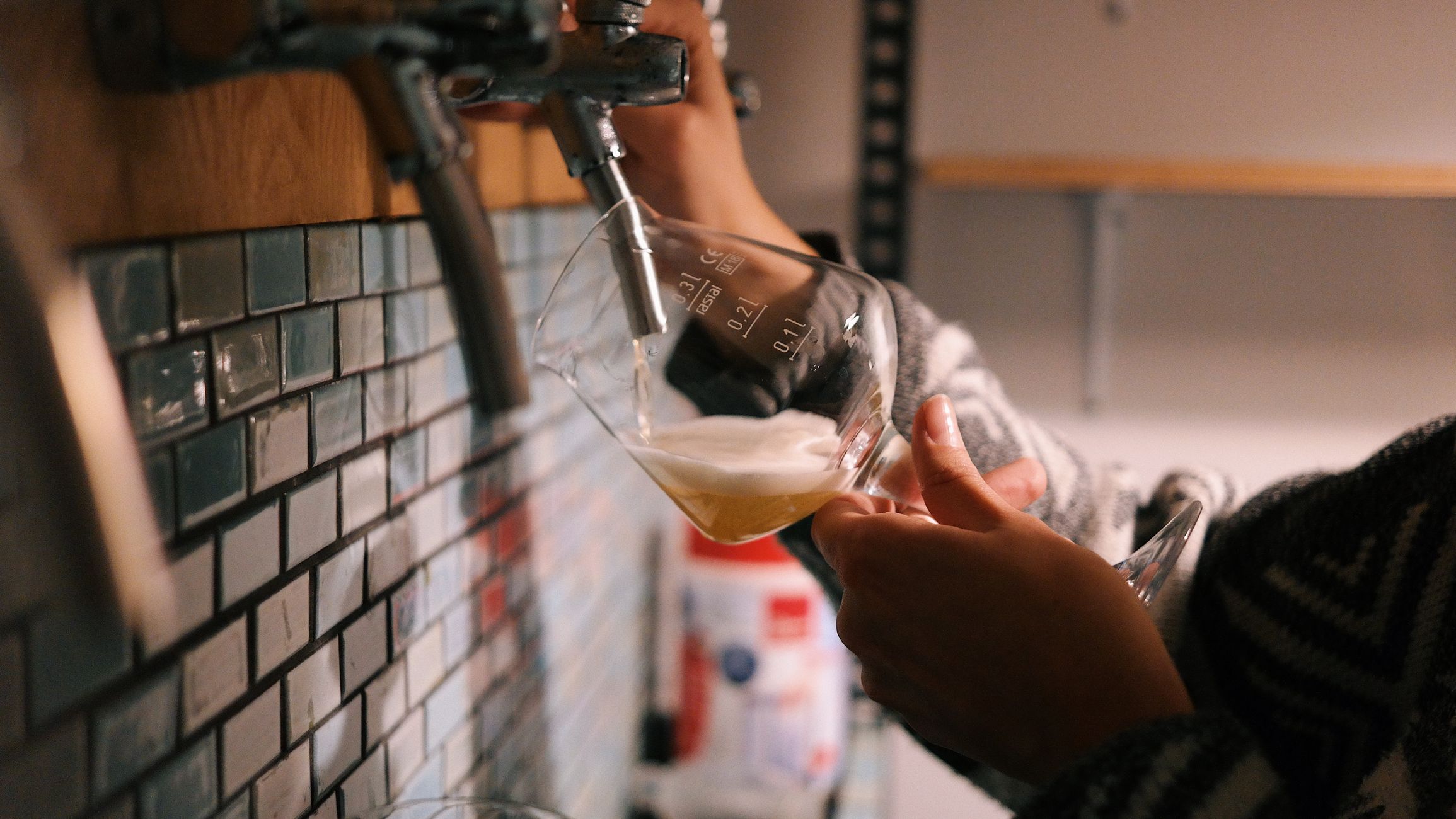 Close-up of a bartender pouring beer into a glass in a cozy indoor setting.