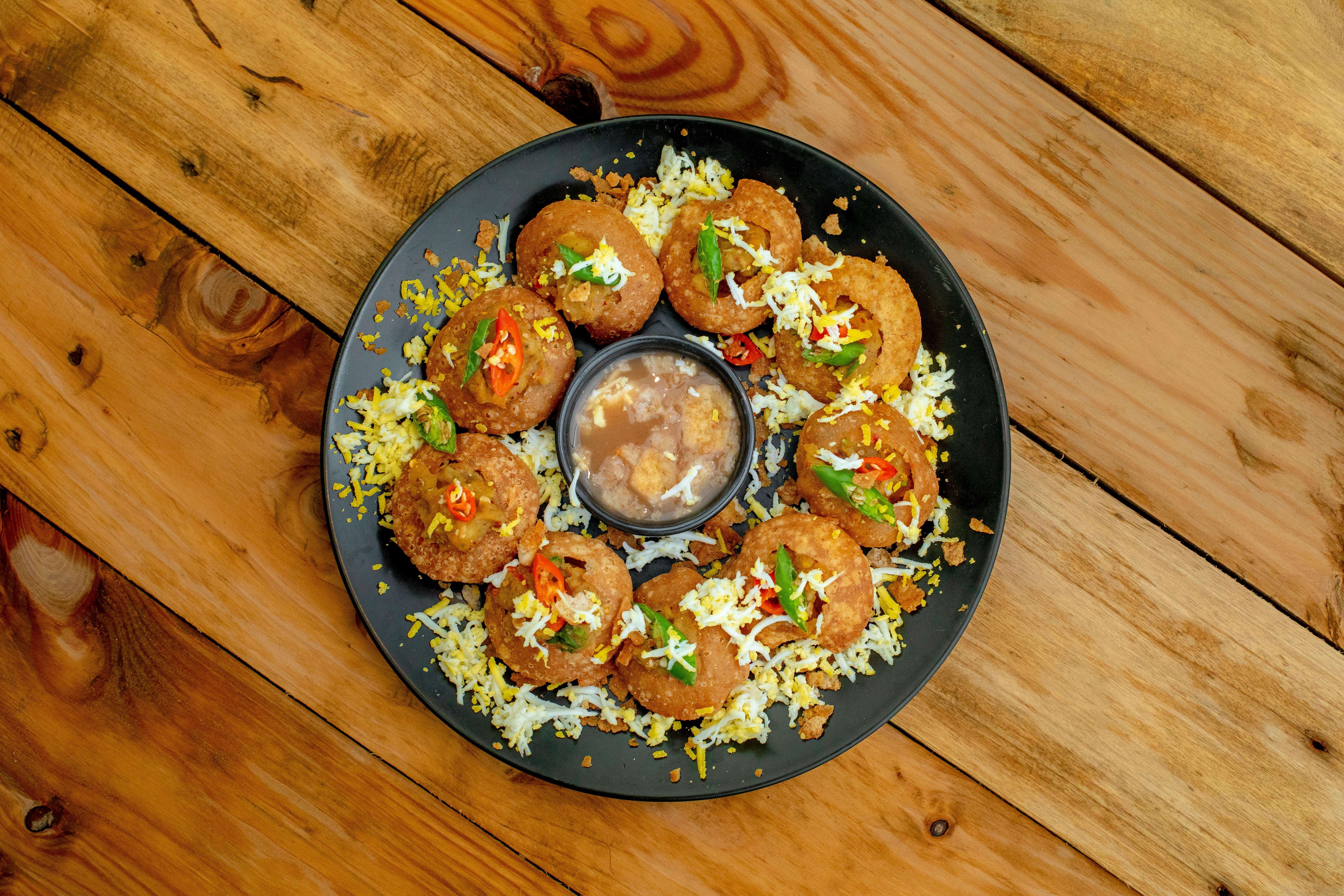 A plate of pani puri with spicy water and chutney