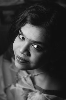 Beautiful high-angle black and white portrait of a smiling woman looking up.