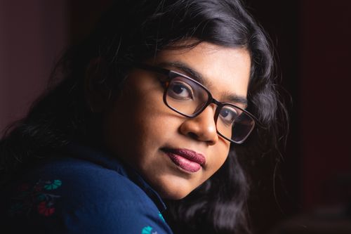Free Close-up portrait of a young woman with glasses and long hair, exuding confidence and warmth. Stock Photo