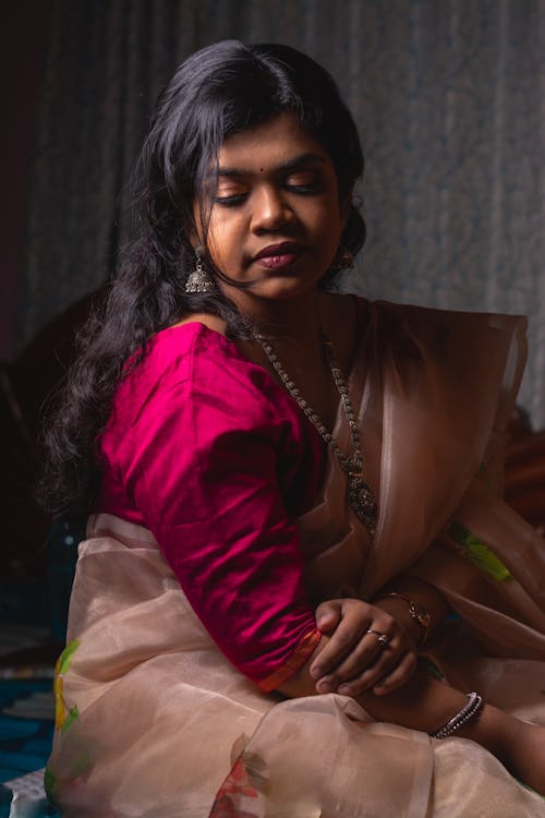 Young Woman in Pink Sari and Magenta Blouse Sitting on a Bed