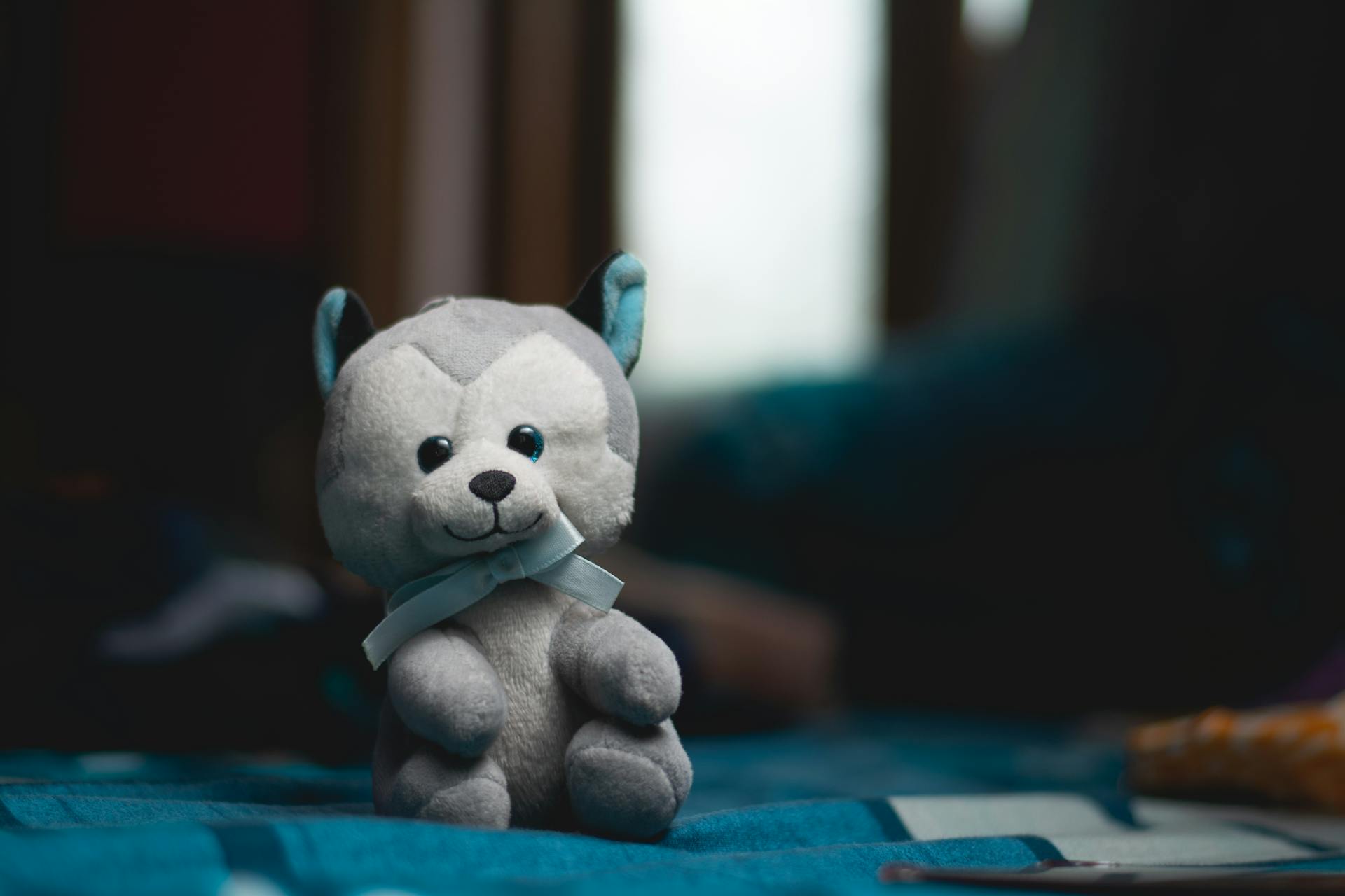 Cute Plush Toy Dog with a Blue Bow Tie Sitting on a Bed