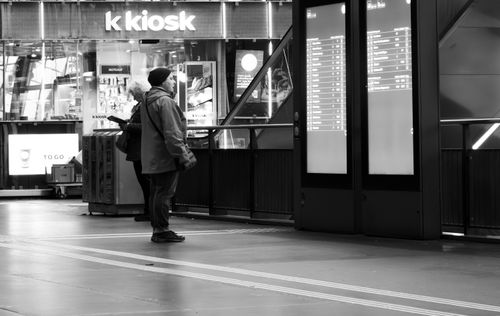 Free A man stands in front of an electronic timetable at Lucerne station in black and white. Stock Photo