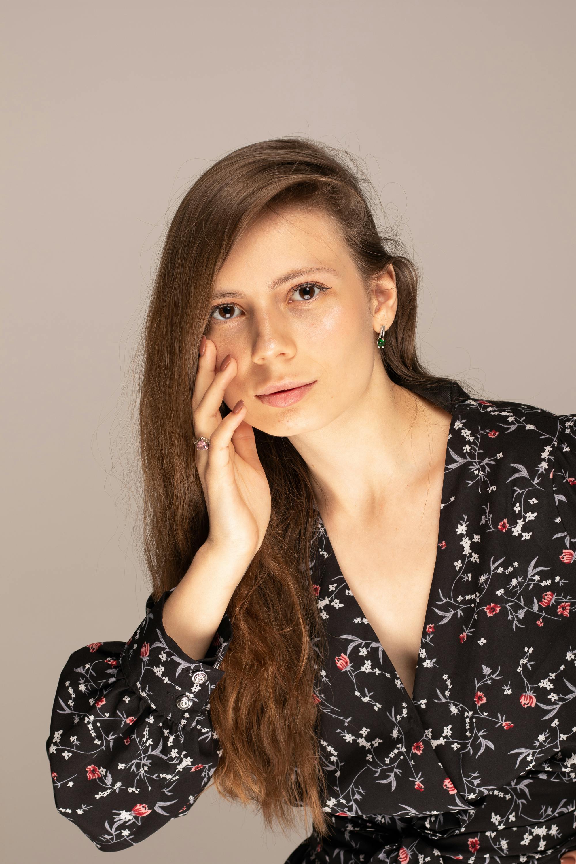 Elegant studio portrait of a woman with flowing hair in a stylish black floral dress.