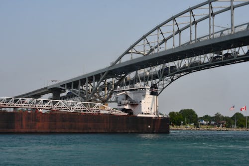 Free Cargo ship passing under the Blue Water Bridge connecting USA and Canada on a clear day. Stock Photo