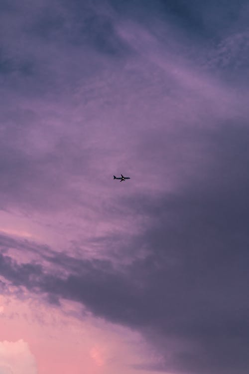 Silhouetted Airplane against Sunset Sky 