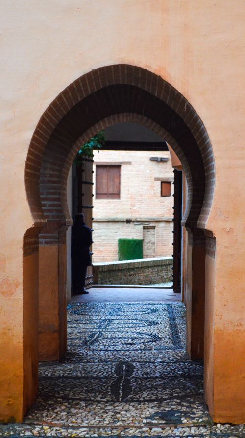 Free View through Moorish archway at Alhambra Palace, Granada, showcasing Islamic architecture. Stock Photo