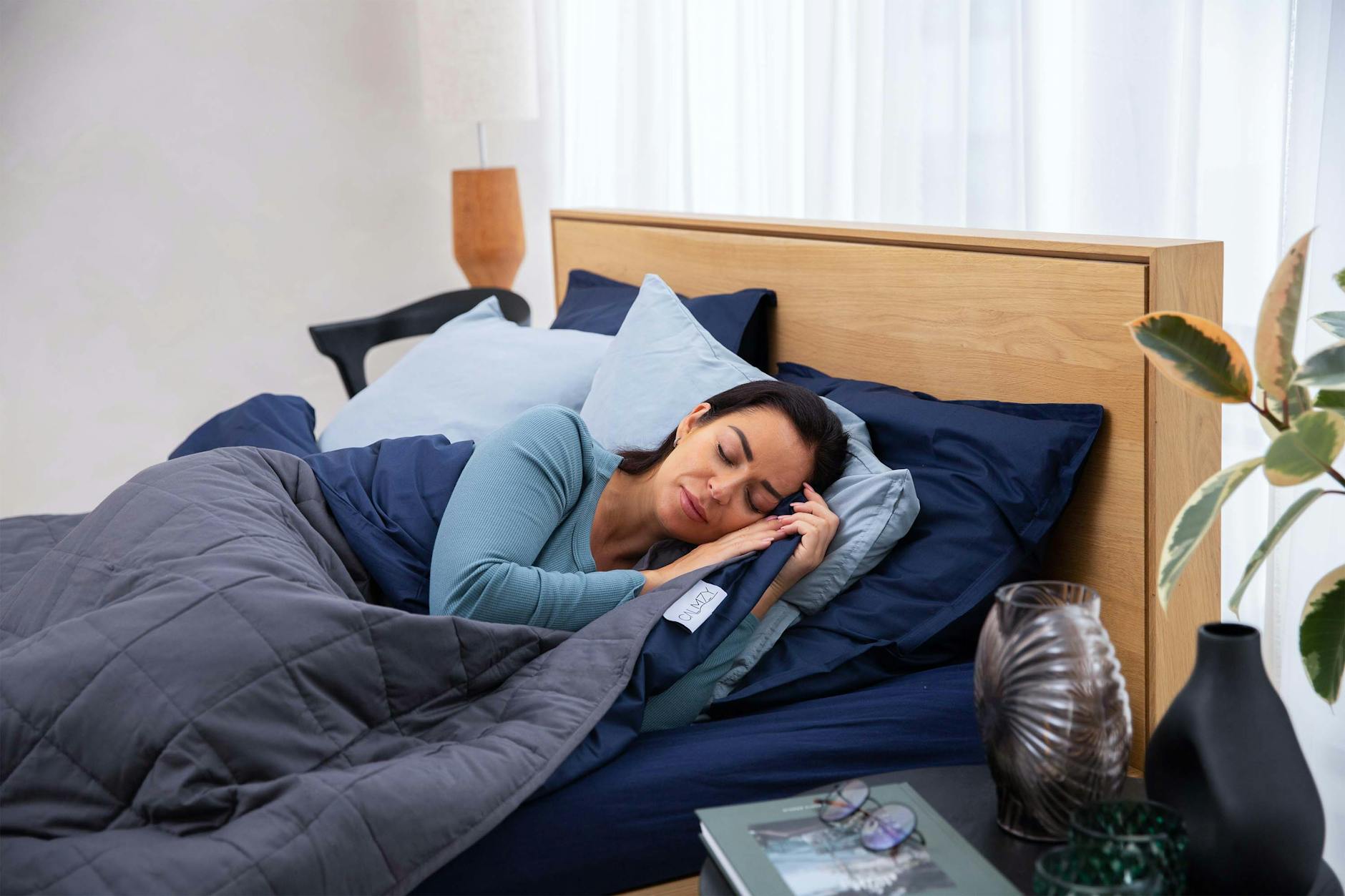 A woman peacefully sleeping on a comfortable bed with soft pillows and a cozy comforter.