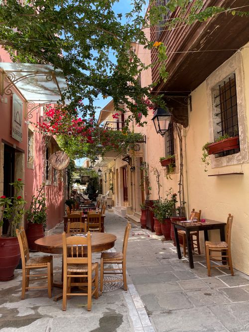 Free Quaint alley with colorful buildings and outdoor cafe in Greece. Stock Photo