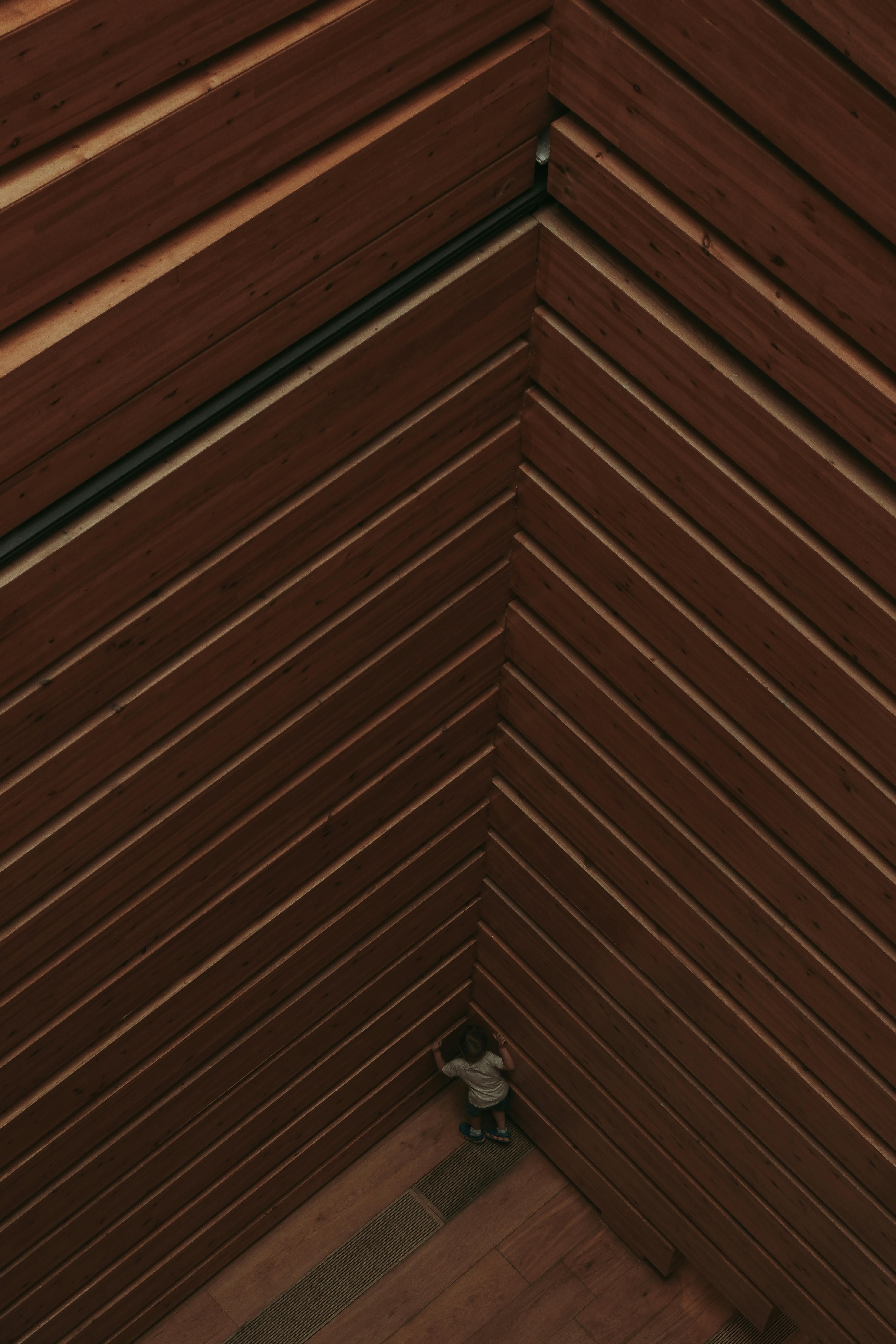 Free High angle view of a child in a wooden paneled corner interior, showcasing artistic patterns. Stock Photo