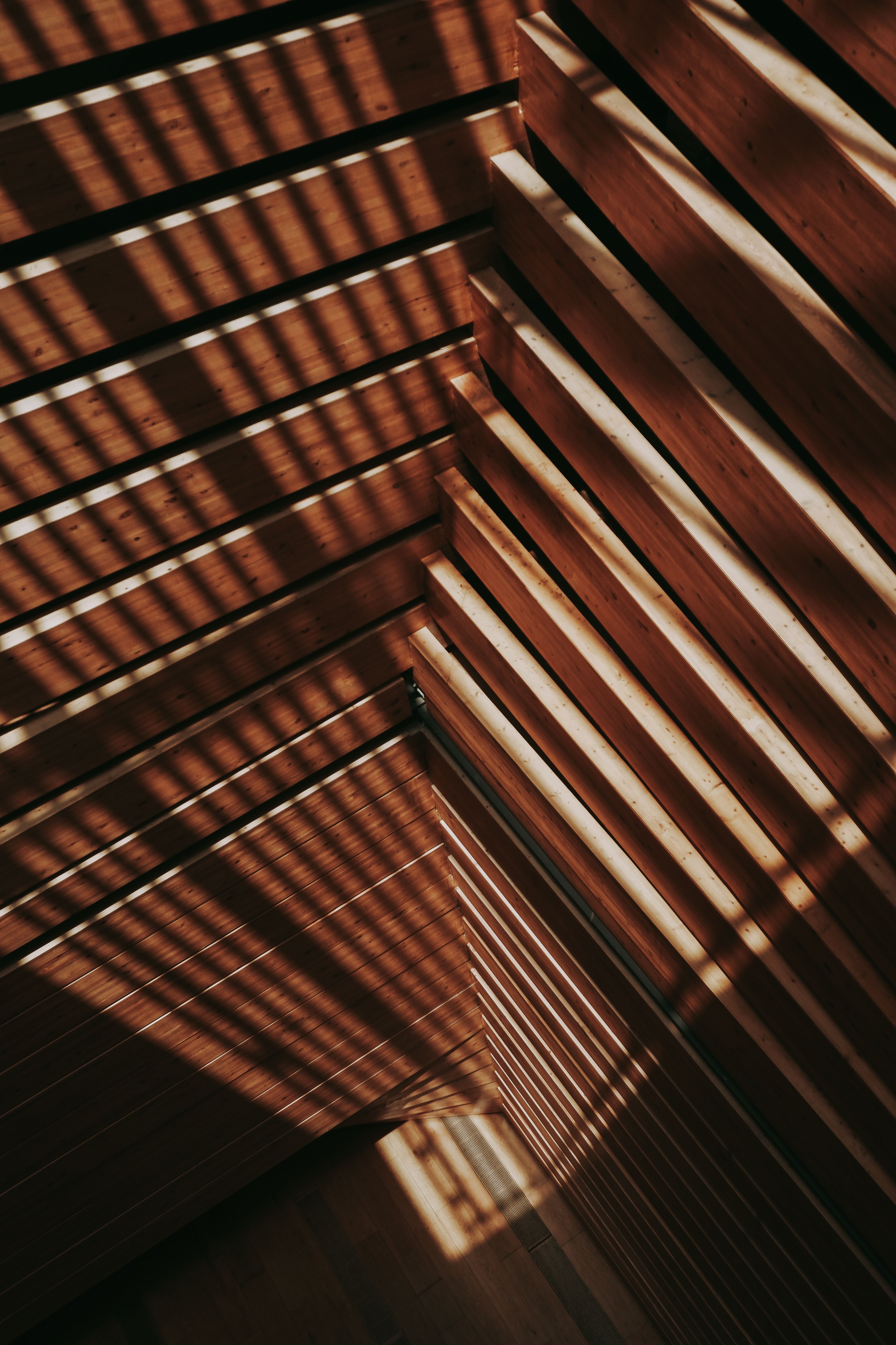 Diagonal wooden beams casting intricate shadows in abstract composition.