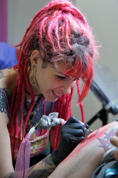 Tattooist with Dreadlocks Doing a Tattoo