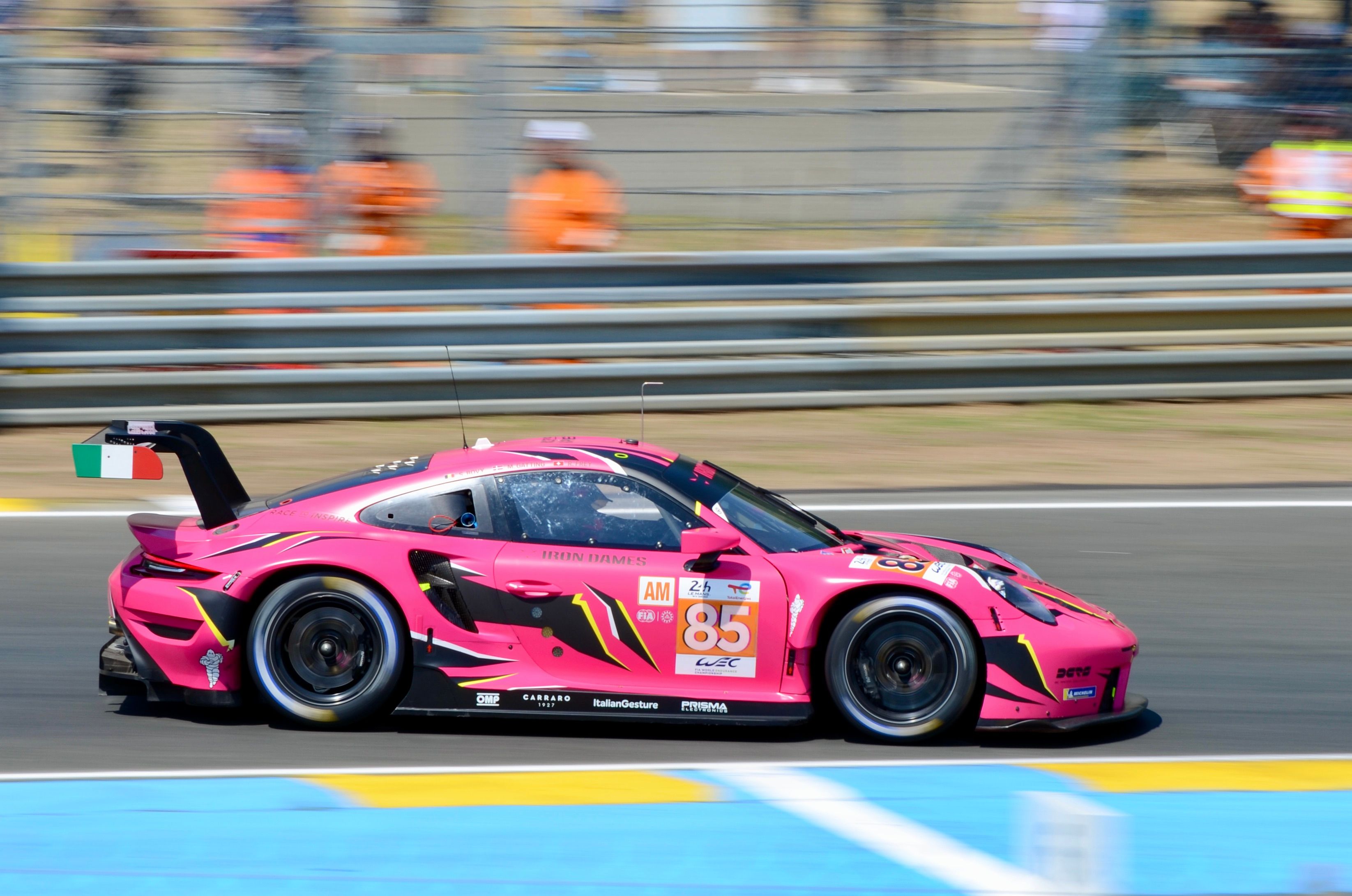 Vibrant pink race car zooming past at Le Mans, France during a motorsport race.