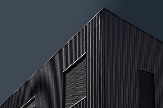 Dark themed modern architectural facade with geometric patterns under a clear sky.