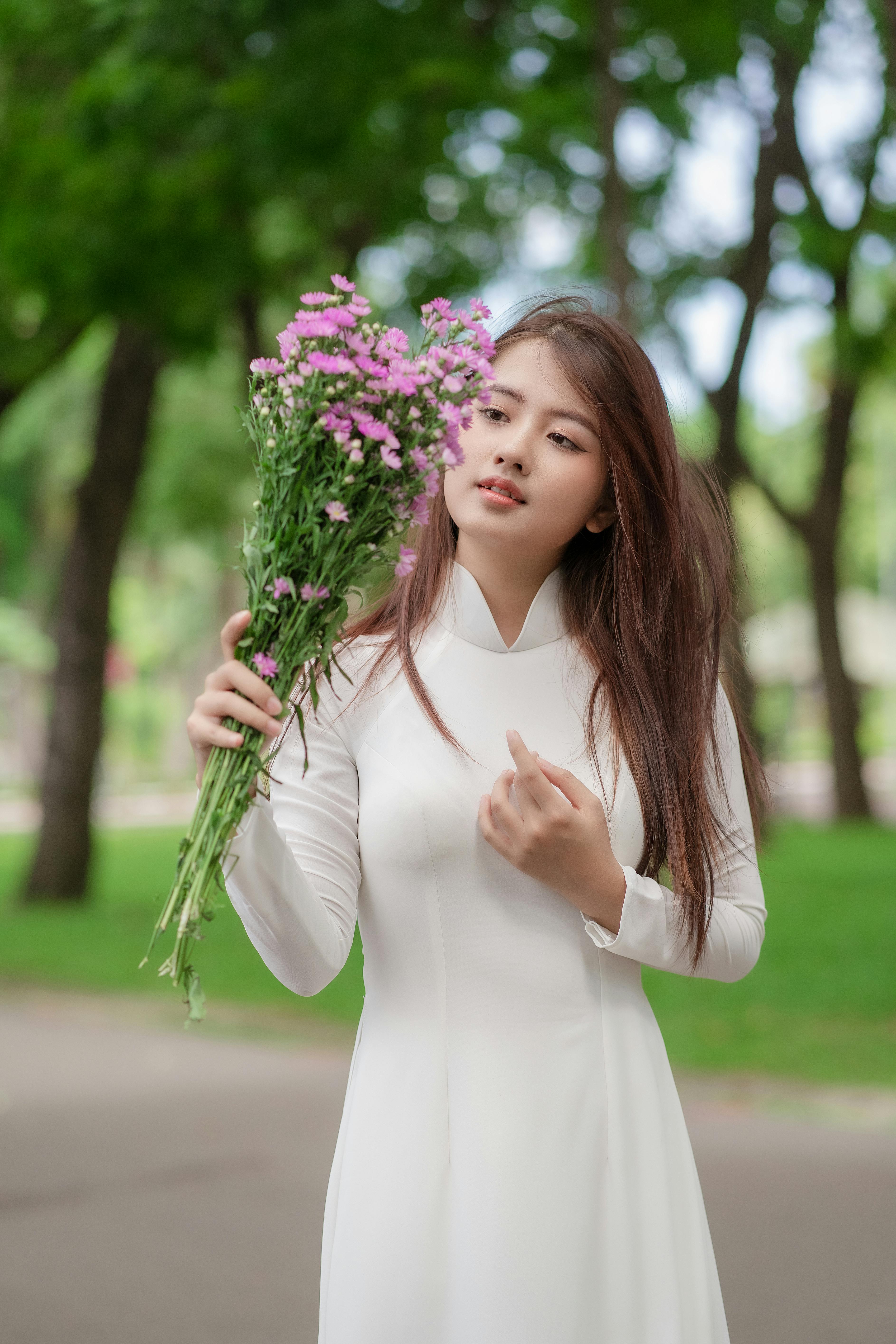 A Woman in White Blouse Holding a Woven Basket with Bunch of White ...