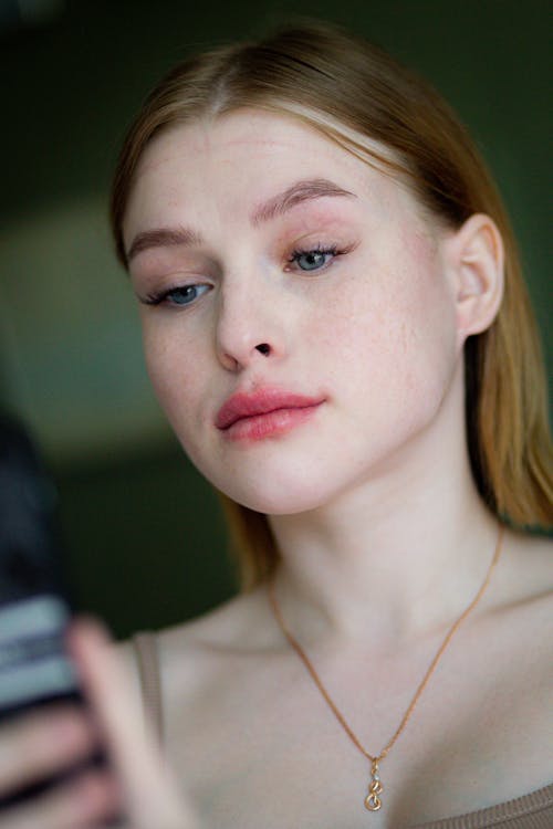 A woman with freckles looking at her cell phone