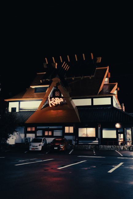 Night view of a traditional Japanese restaurant with parked cars in Toyohashi, Japan, showcasing distinctive architecture.
