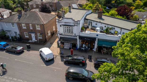 A vibrant aerial view of Thames Ditton featuring shops, cars, and houses on a sunny day.