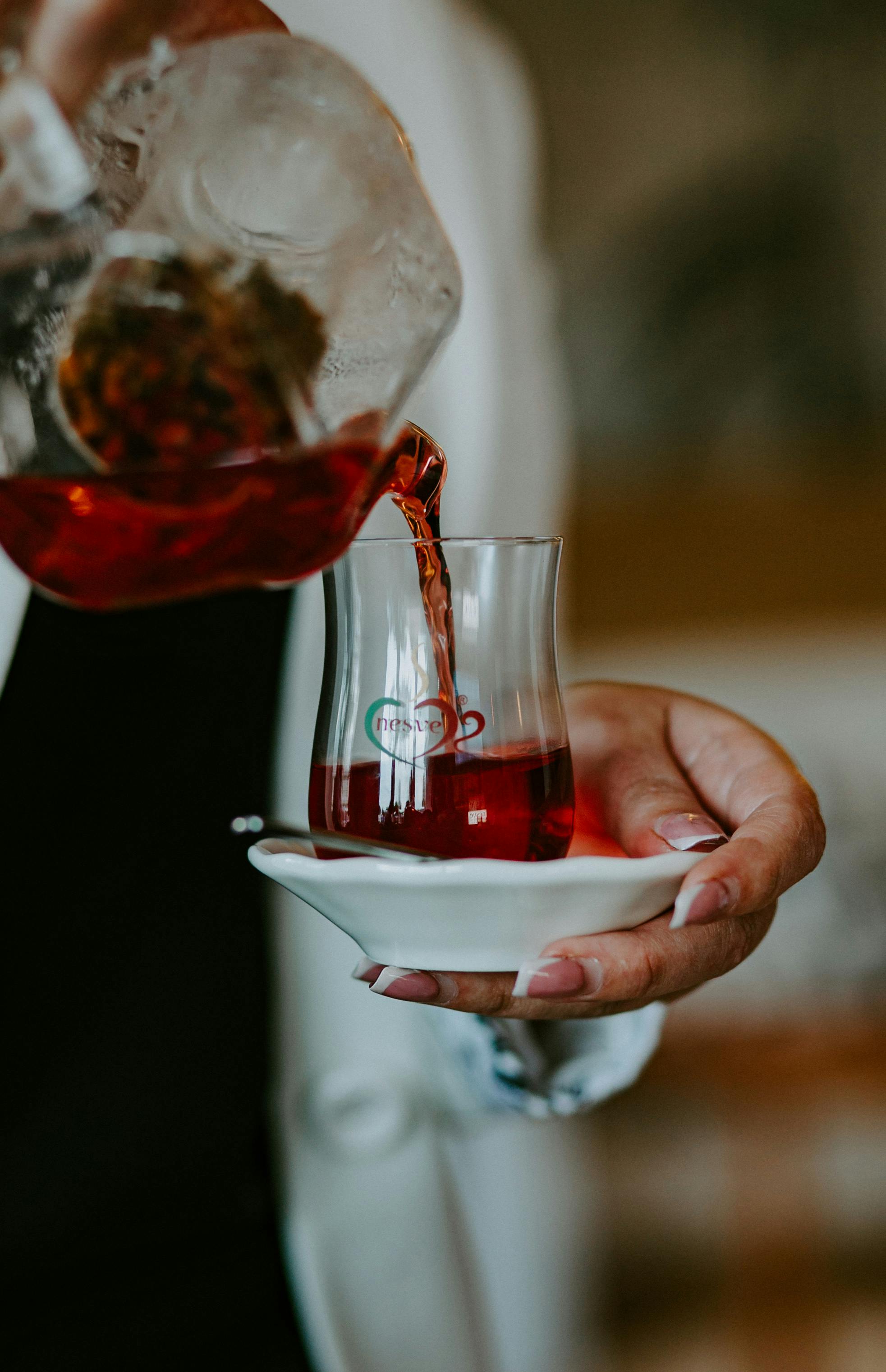 close up of woman pouring tea from a pot into a glass