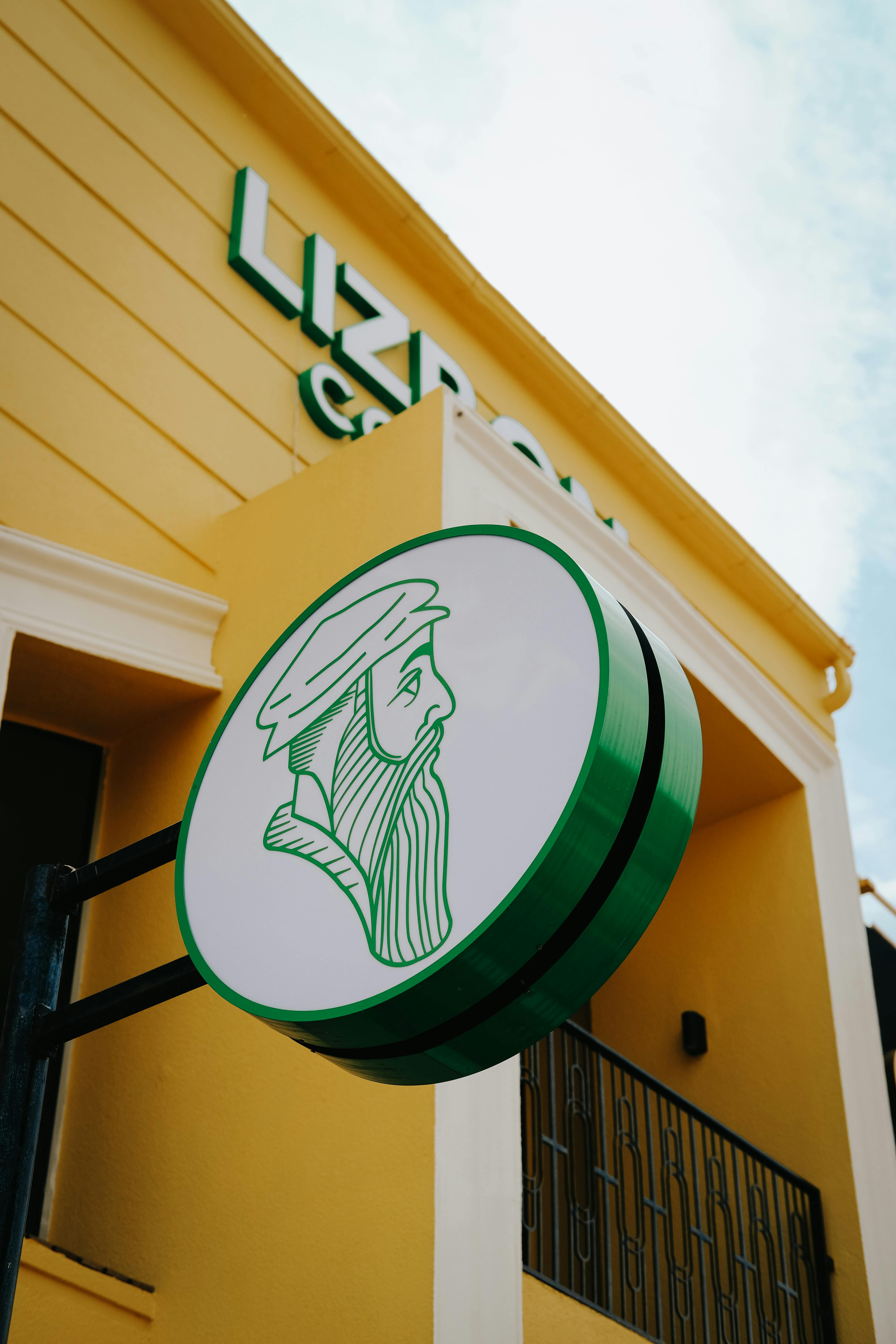 Low-angle view of a cafe sign with a graphic design on a yellow building in Ankara.