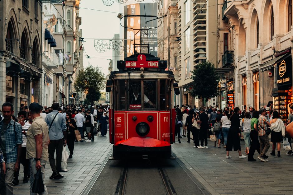 A bustling scene of Istanbul's Istiklal Street featuring the iconic red tram surrounded by city life.