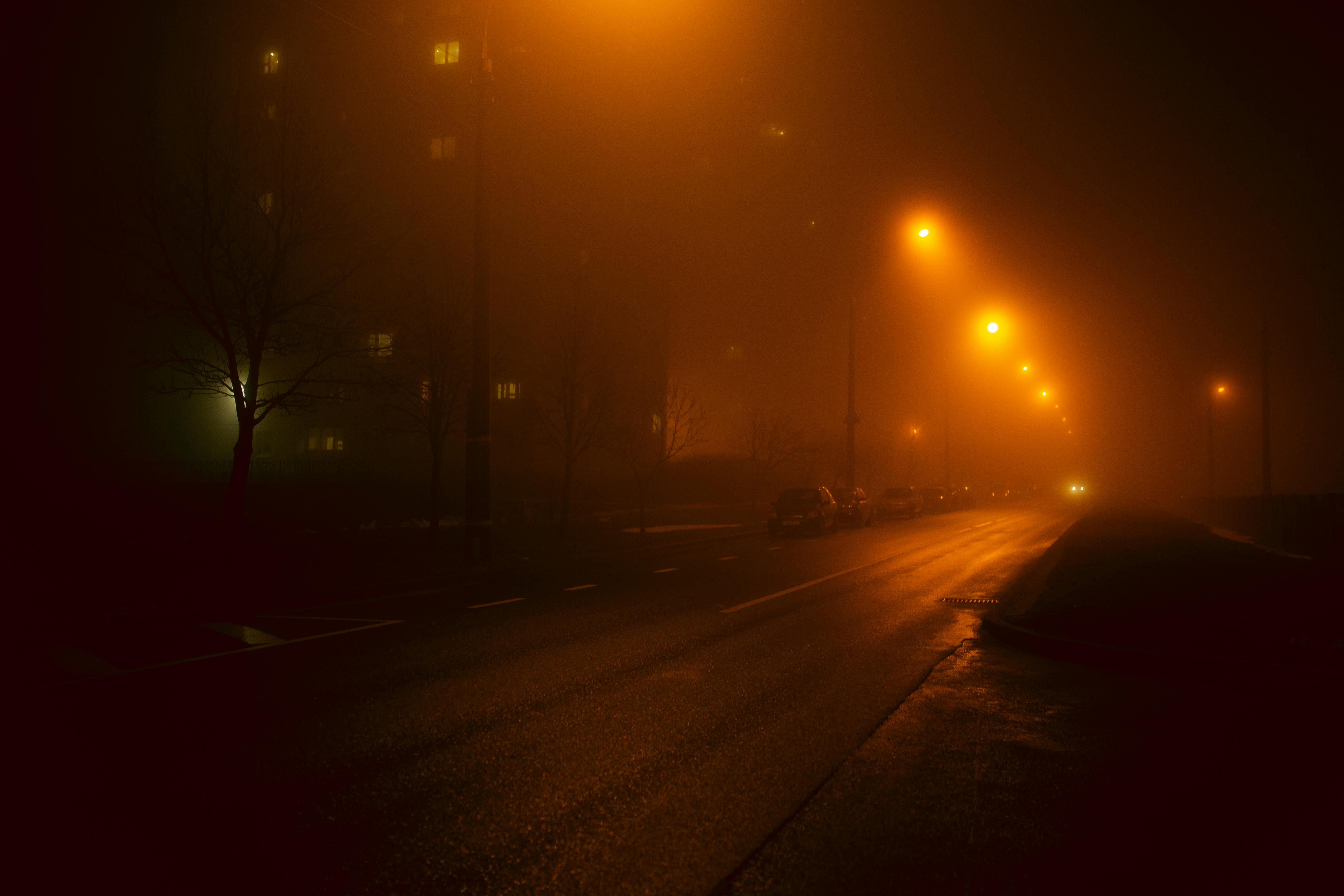Misty urban street in Minsk at night, illuminated by foggy streetlights, creating an atmospheric scene.