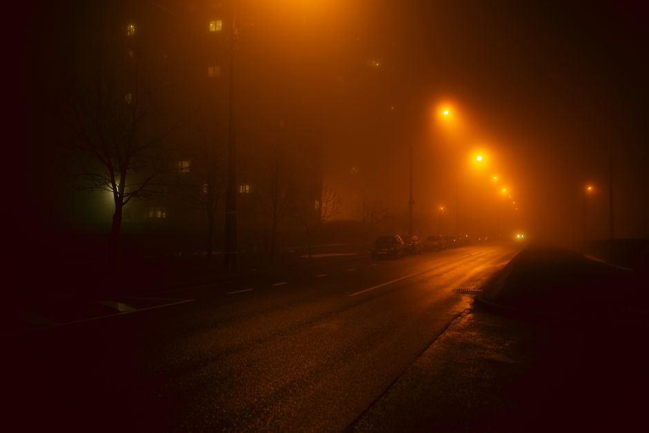 Misty urban street in Minsk at night, illuminated by foggy streetlights, creating an atmospheric scene.