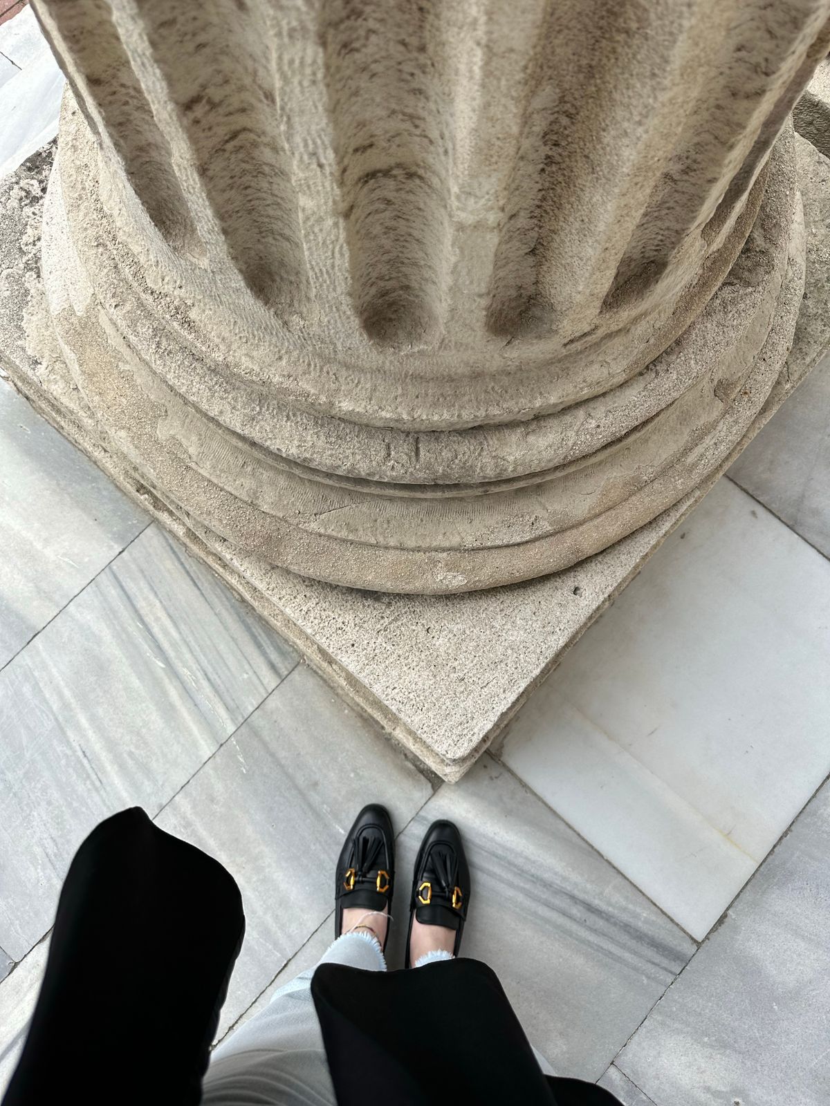 A woman's shoes as she stands by a column — the elegant flat